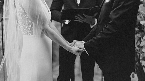 a bride and groom holding hands with an officiant presiding